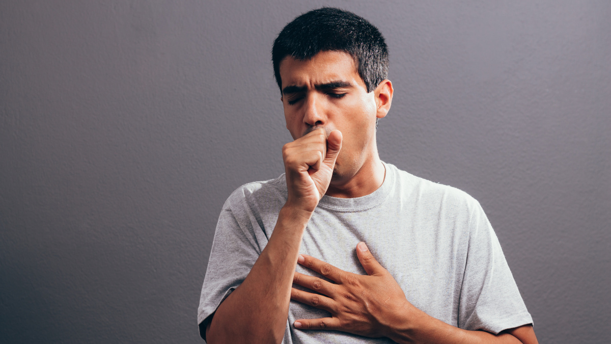 Man, coughing and holding his chest