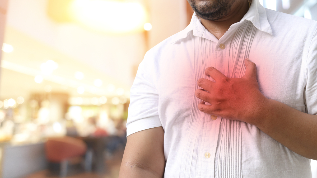 Man in shirt experiencing a sharp pain in his chest 